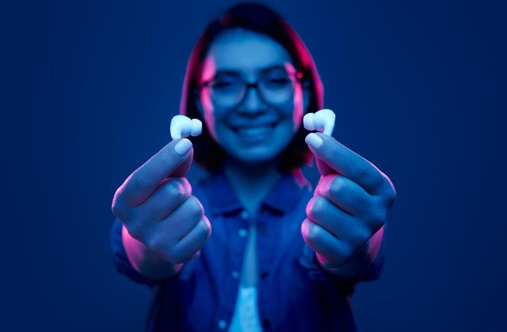 Cheerful woman showing TWS earphones