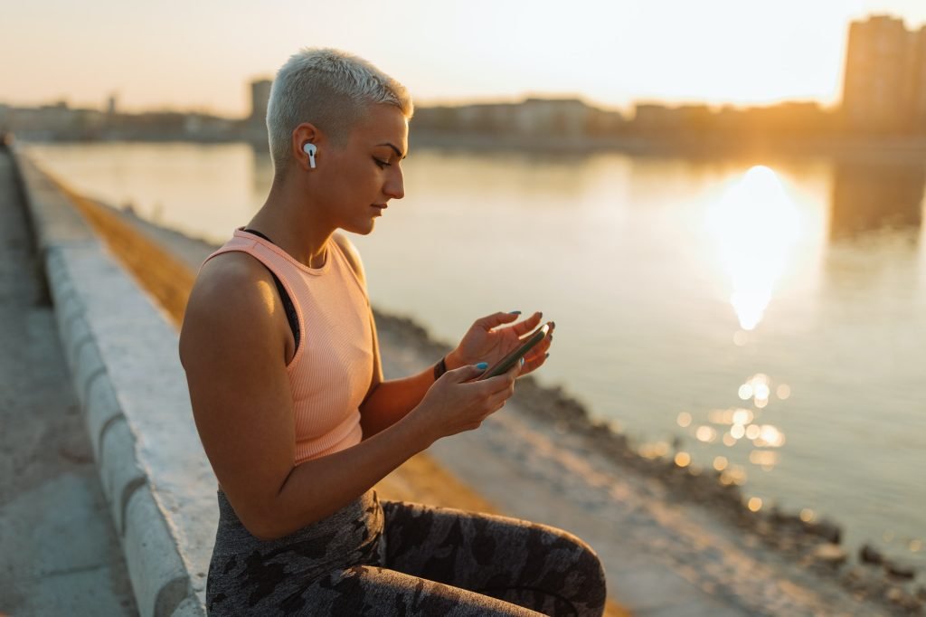 Relaxed sportswoman enjoying good music on quay