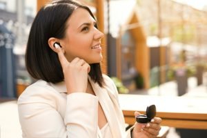 Woman inserts earbuds into her ear and turns them on to listen to music